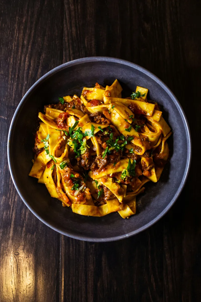 Tagliatelles fraîches maison nappées de sauce tomate et viande, parsemées de persil