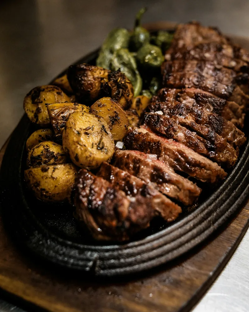 Viande grillée tranchée servie avec pommes de terre rôties et piments verts